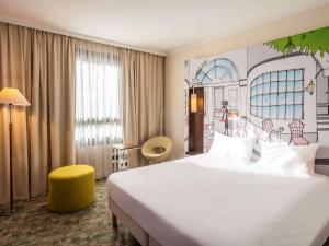 Pokój hotelowy z dużym białym łóżkiem i żółtym stołkiem w obiekcie ibis Styles Evry Courcouronnes Hotel and Events w mieście Courcouronnes