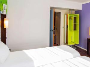 - une chambre avec un lit blanc et une porte verte dans l'établissement ibis Styles Evry Courcouronnes Hotel and Events, à Courcouronnes