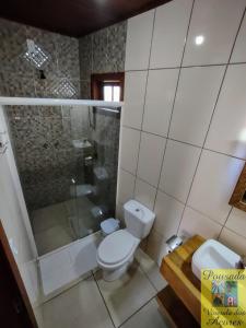 uma casa de banho com um WC, um chuveiro e um lavatório. em Pousada Vivenda dos Açores em Penha