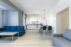 a living room with a blue couch and a kitchen at GERBERA APARTMENT 3к ЖД Вокзал Аквапарк Центр in Novosibirsk