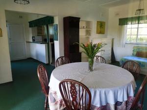 Una mesa de comedor con un jarrón de flores encima. en BillsBest Greengates Cottages, en Port Edward