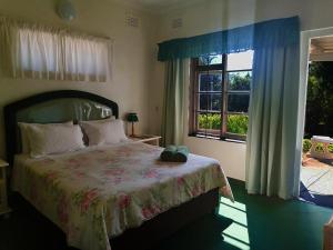 un dormitorio con una cama y una ventana en BillsBest Greengates Cottages, en Port Edward