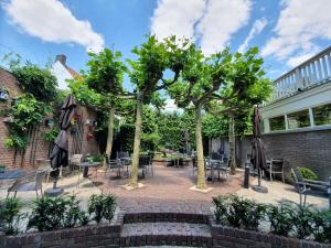 a patio with tables and chairs and trees at Slapen Bij Brownies & Downies in Valkenswaard