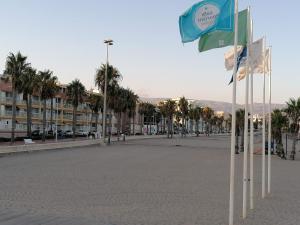 a street with palm trees and flags in the sand at Apartamento ROQUETAS DE MAR MUY CERCA PLAYA in Roquetas de Mar