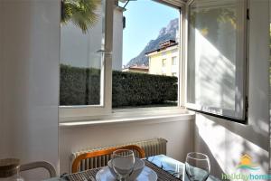 a table and a window with a view of a building at Green relax apartment - Holiday Home Garda Trentino in Riva del Garda