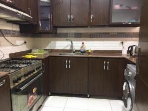 a kitchen with wooden cabinets and a sink and a stove at Ramco For Furnished Apartments And Accommodation Compound Leila in Cairo