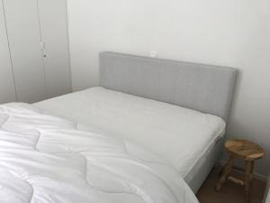 a white bed with a wooden stool next to it at Zilverzand aan zee - frontaal zeezicht in Koksijde