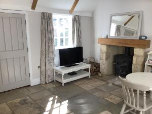 een woonkamer met een televisie en een open haard bij Courtyard Cottage in Stroud