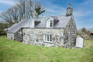 una vieja casa de piedra en una colina en Ty-Gwyn Cottage, en Clynnog-fawr