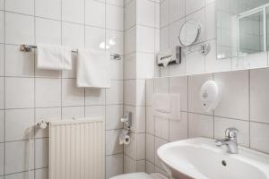 a bathroom with a sink and a toilet and a mirror at acora Bonn Living the City - Apartments in Bonn +33 photos