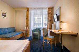 a hotel room with a bed and a desk and a couch at acora Bonn Living the City - Apartments in Bonn