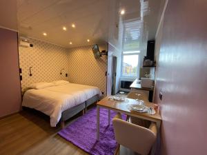 Schlafzimmer mit einem Bett und einem Tisch mit Stühlen in der Unterkunft Capstay Color Valenciennes & Netflix in Saint-Léger