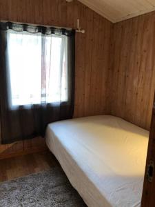 um pequeno quarto com uma cama e uma janela em Beautiful 3 Bed Cottage in Ytteroy with seaview em Ytteroy