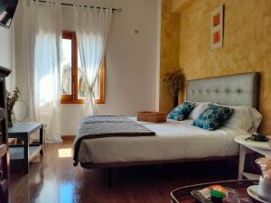 a bedroom with a bed with blue pillows and a window at Hotel Rural Luna Llena in Torremocha de Jarama
