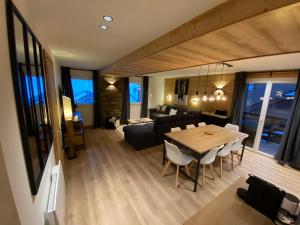 L'Etesy, rénové en 2021, pied des pistes et spa في مونجينيفر: غرفة معيشة وغرفة طعام مع طاولة وكراسي