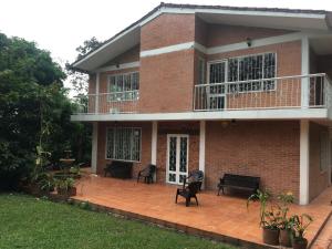 Cette maison en briques dispose d'un balcon et de bancs sur une terrasse. dans l'établissement Kaliawiri Bird Lodge & reserve, à Villavicencio