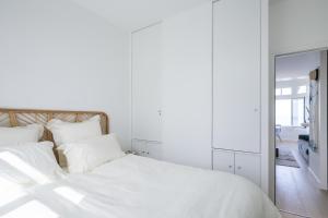 a white bed with white pillows and a mirror at La Perle Marine in Dinard