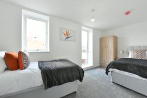 a bedroom with two beds and two windows at The Breath Taking Cube in Pontefract