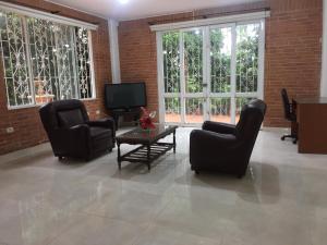 a living room with two chairs and a television at Kaliawiri Bird Lodge & reserve in Villavicencio