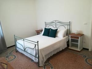 una camera da letto con un letto bianco con cuscini verdi di La casa di Via Defferrari a Noli
