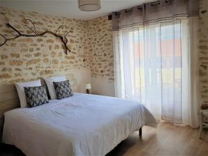 a bedroom with a bed and a large window at Le pré de la rue in Bouesse
