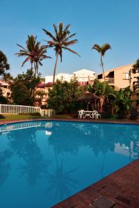 a swimming pool with palm trees in the background at La Lucia Sands Beach Resort in Durban