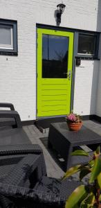 JaBaKi Green Studio في هوفدوربْ: باب أخضر على مبنى به طاولات وكراسي