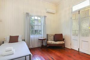 a bedroom with a bed and a chair and a window at Walk to the Charming Character Home in Brisbane