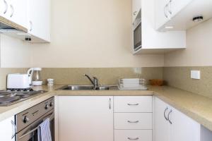 a kitchen with white cabinets and a sink at Charming 1 Bedroom Apartment in Vibrant South Yarra in Melbourne