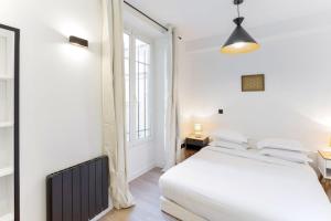 a white bedroom with a bed and a window at Amazing 2 Bedroom Parisian flat in Paris