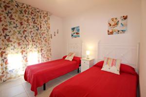 two beds in a room with red sheets at Altos de Nuevo Vera in Vera +17 photos