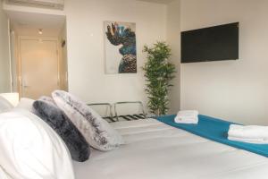 um quarto com uma cama branca com almofadas em 1 Bed Studio Apartment Near Eagle Street em Brisbane