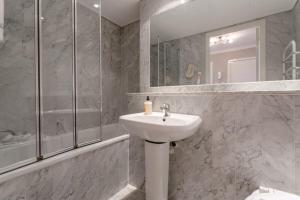 a white bathroom with a sink and a shower at Bright Modern One-Bed with Stunning View of Thames in London