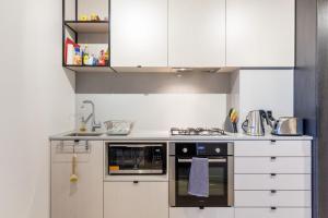 a kitchen with white cabinets and an oven at Modern 1 Bedroom in Tranquil Parklands in Melbourne