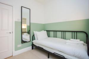 Schlafzimmer mit einem Bett mit weißer Bettwäsche und einem Spiegel in der Unterkunft Stylish & Modern 3 Bed Flat in NW London with Garden in London