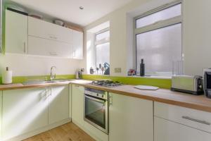 ロンドンにあるModern 1 Bed Flat in Central Londonの白いキャビネット、シンク、窓付きのキッチン