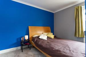 ロンドンにあるSpacious 3 Bedroom House with Garden in Bermondseyの青いベッドルーム(木製ヘッドボード付きのベッド1台付)