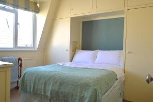 1 dormitorio con 1 cama con cabecero azul en Lovely Top Floor Flat in Leafy Fulham, en Londres