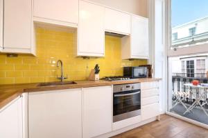 ブライトン＆ホーブにあるGorgeous Central Apartment with Sea Viewsの白いキャビネットと黄色の壁が備わるキッチン