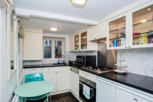 eine Küche mit weißen Schränken und einem blauen Stuhl in der Unterkunft Cosy 1 Bedroom Apartment Near Harrods Knightsbridge in London