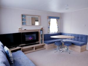 uma sala de estar com um sofá azul e uma mesa em The Abi Joseph @Combe Haven em Hastings