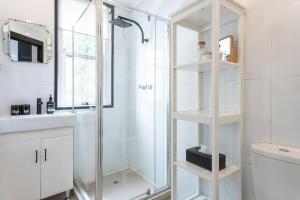 a white bathroom with a shower and a sink at Boutique Studio Apartment at Potts Point in Sydney
