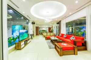a living room with red couches and a flat screen tv at An Phú Villa and Golf FLC Sầm Sơn in Sầm Sơn