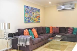 a living room with a brown couch with colorful pillows at Bright 2 Bedroom Apartment In A Great Location in Perth