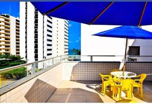 a table and chairs with a blue umbrella on a balcony at Hotel Porto Segur0 in Recife