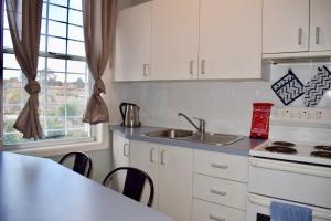 a kitchen with white cabinets and a sink and a stove at Comfortable 3 Bedroom Apartment In Trendy Haberfield in Sydney