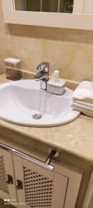 lavabo blanco en el baño con espejo en Bevs ground floor Roda Golf Apartment!, en San Javier