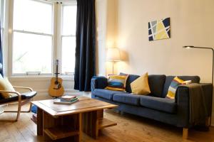 エディンバラにあるBeautiful Traditional 3 Bedroom Apartment in Edinburghのリビングルーム(青いソファ、ギター付)