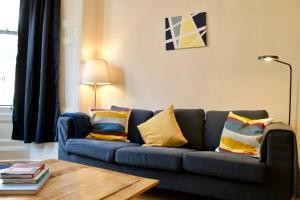 エディンバラにあるBeautiful Traditional 3 Bedroom Apartment in Edinburghのリビングルーム(カラフルな枕と青いソファ付)