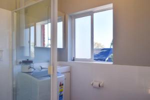 a bathroom with a sink and a toilet and two windows at Sun-Drenched 1 Bed Studio Apartment In Newtown in Sydney